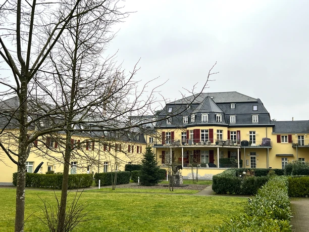 Haus Venauen <p>Historisches gelbes Gebäude mit roten Fensterläden und einem gepflegten Garten in Rösrath.</p>