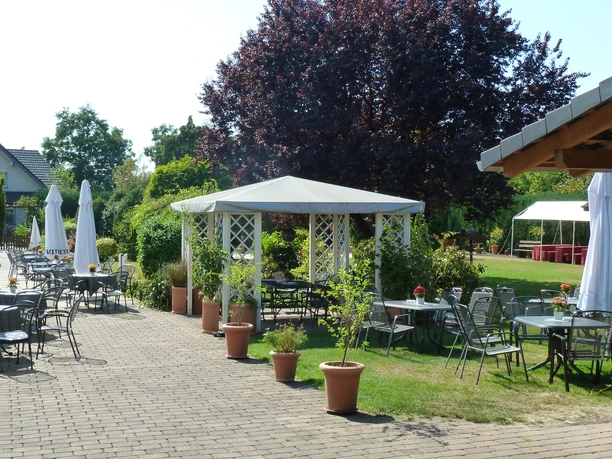 Biergarten vom Hotel-Restaurant Meermeier Ein Biergarten mit Tischen, Stühlen und Sonnenschirmen auf einem gepflasterten Weg neben einem Pavillon.