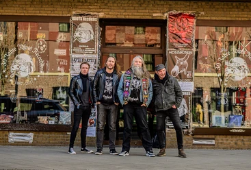 2023 Weckörhead II.jpg Vier Männer stehen lächelnd vor einem Schallplattenladen, bekleidet mit Lederjacken und Band-Shirts.