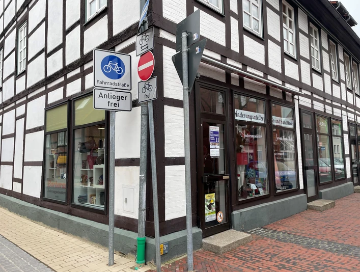 Dombrowsky.jpg Fachwerkgeschäft an einer Straßenecke, Schilder weisen auf Fahrradstraße und Einfahrtverbot hin.