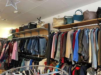 Dombrowsky2.jpg Einladende Asiatmosphäre eines Secondhand-Ladens mit vielfältiger Auswahl an Kleidung in verschiedenen Farben.