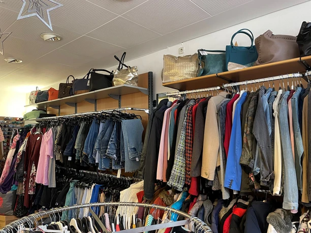 Dombrowsky2.jpg Einladende Asiatmosphäre eines Secondhand-Ladens mit vielfältiger Auswahl an Kleidung in verschiedenen Farben.