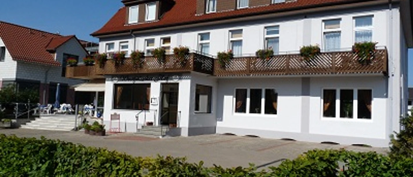 Außenansicht Westfälischer Hof.JPG Ein dreistöckiges Gebäude mit rotem Dach, Blumenkästen an den Balkonen, umgeben von einem Garten.