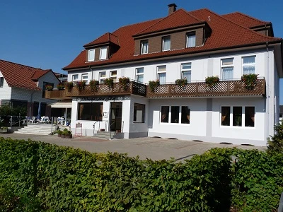 Außenansicht Westfälischer Hof.JPG Ein dreistöckiges Gebäude mit rotem Dach, Blumenkästen an den Balkonen, umgeben von einem Garten.