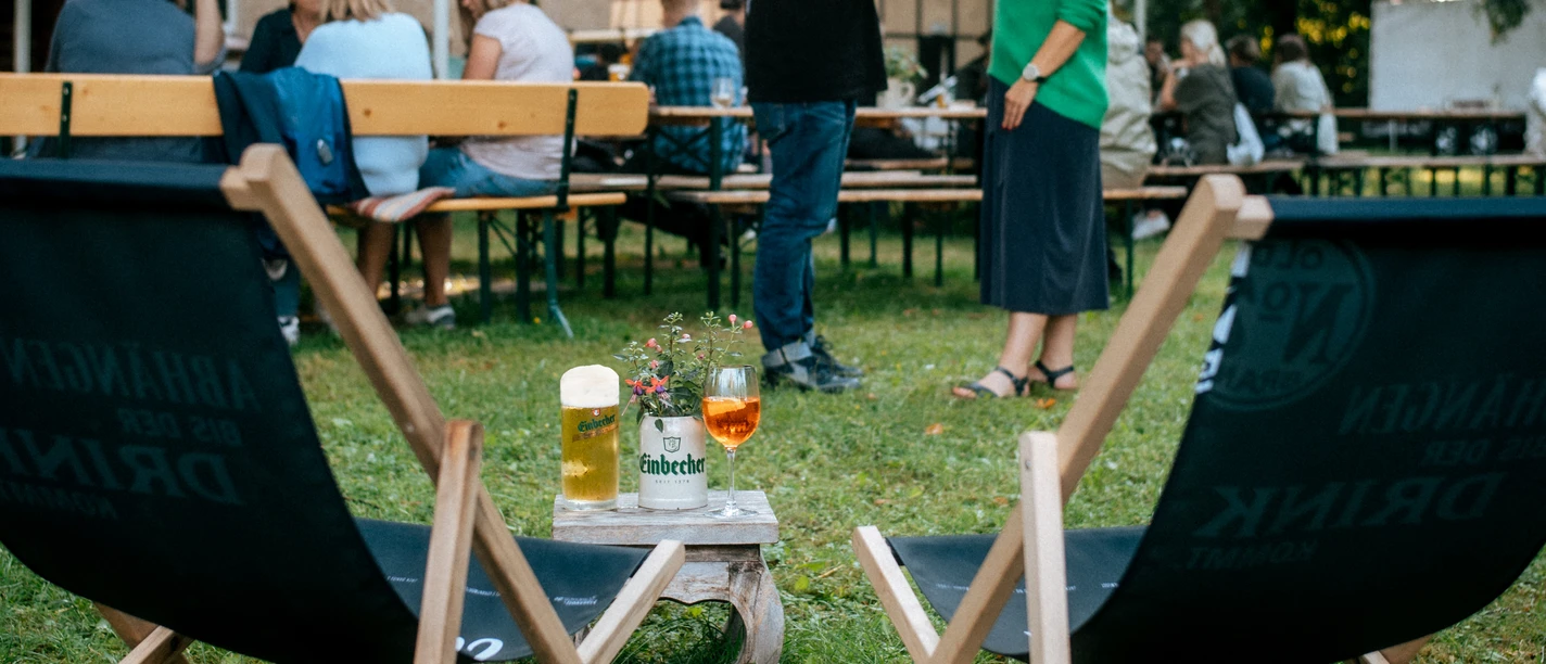 Biergarten in Einbeck Wiese mit Stühlen, Getränken und Menschen.