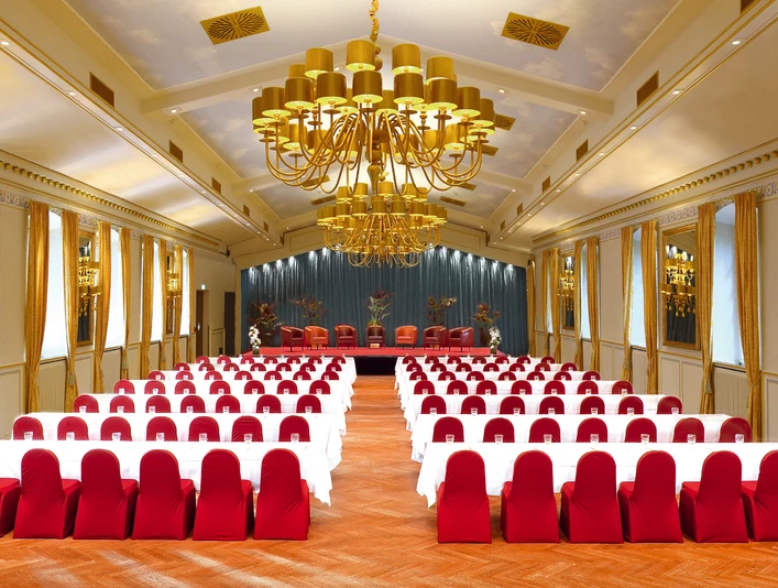 015_festsaal_parlament_blau.jpg Eleganter Ballsaal mit goldenen Kronleuchtern, roten Stuhlbezügen und spiegelverzierten Wänden.Elegant ballroom with golden chandeliers, red chair covers and mirrored walls.