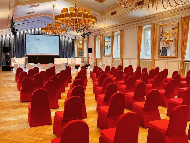 Großer Saal Elegant, empty conference room with red chairs, golden chandeliers and wooden floor.</p> <p