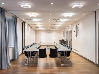 Apollo Tagungsraum Konferenzraum mit rechteckigem Tisch, zehn Stühlen, Holzboden und moderner Beleuchtung.Conference room with rectangular table, ten chairs, wooden floor and modern lighting.