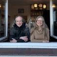 Fenstermusik mit Stefan Römer Stefan Römer und eine Frau blicken lächelnd durch ein geöffnetes Fenster mit Büchern im Hintergrund.