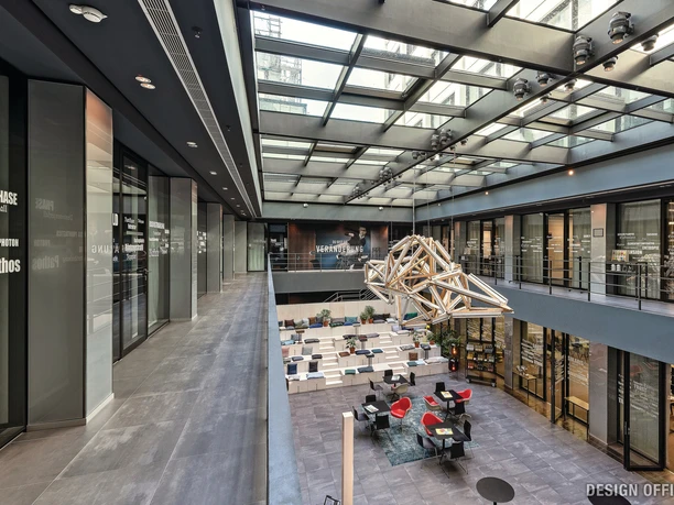 Modern office environment with light-flooded atrium, lounge area and an impressive ceiling object.