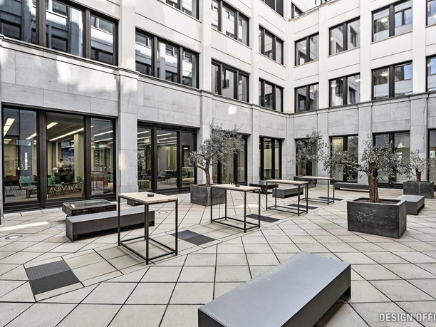 Inner courtyard with modern planters, tables and benches, surrounded by office buildings.</p> <p