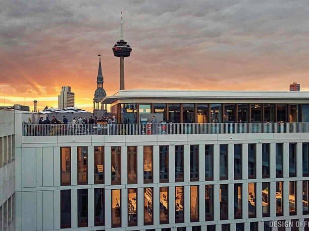 Terrasse Blick auf Skyline mit Rheinturm bei Sonnenuntergang, modernes Gebäude im Vordergrund.</p>