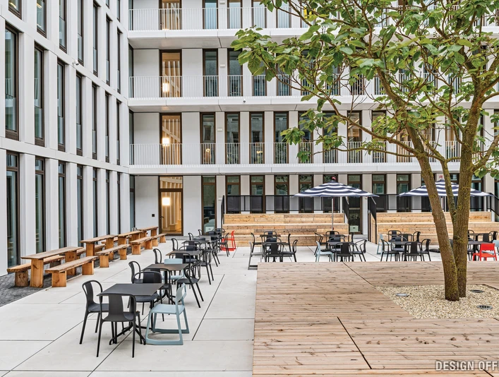 Innenhof Moderner Innenhof mit Sitzbereichen, Bäumen und hohen Glasgebäuden im Hintergrund.</p>Modern inner courtyard with seating areas, trees and tall glass buildings in the background.</p> <p