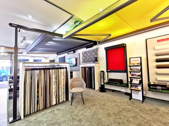 Raumausstattung Weist Ein heller Ausstellungsraum mit Sonnenschutzprodukten, Stoffmustern und modernen Sitzgelegenheiten.