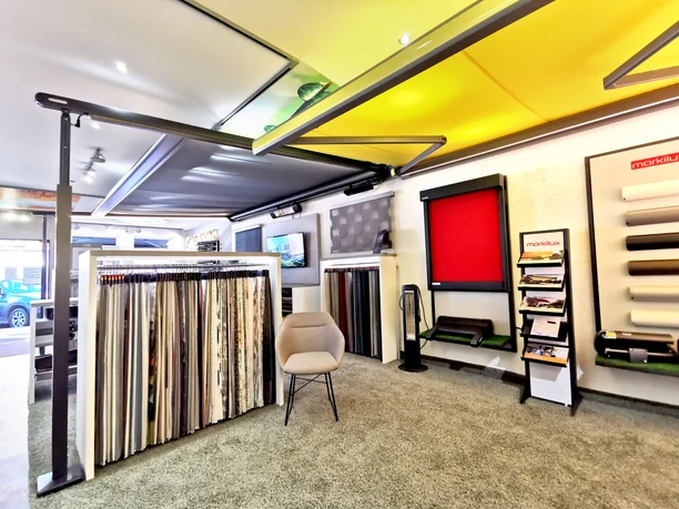 Raumausstattung Weist Ein heller Ausstellungsraum mit Sonnenschutzprodukten, Stoffmustern und modernen Sitzgelegenheiten.