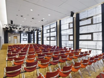 Kleiner Saal im Medio Ein moderner Konferenzraum mit roten Stühlen und großen Fenstern für viel Tageslicht.A modern conference room with red chairs and large windows for plenty of natural light.