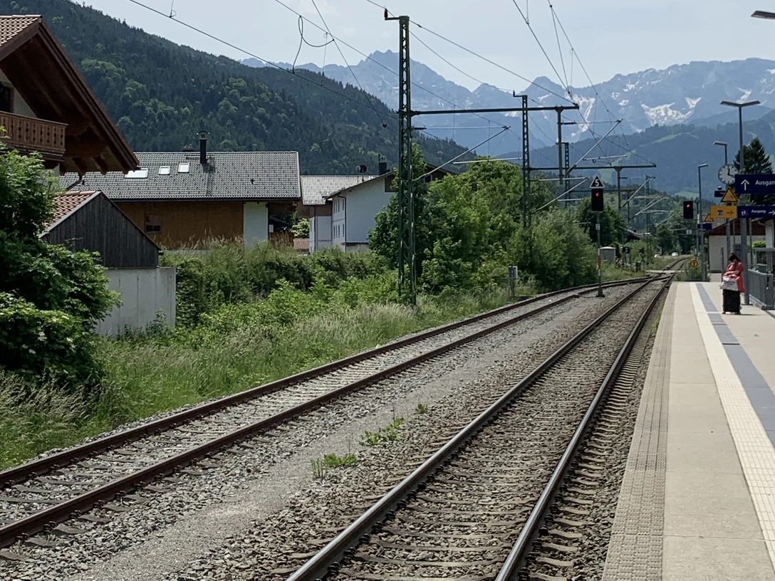 IMG_7708.jpg Bahngleise mit Oberleitungen, linker Hand Häuser und in weiter Ferne das Wettersteinmassiv