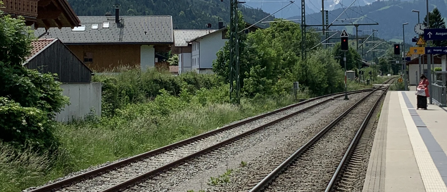 IMG_7708.jpg Bahngleise mit Oberleitungen, linker Hand Häuser und in weiter Ferne das Wettersteinmassiv