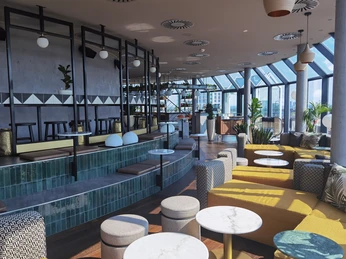 Bar Botanik Blick zur Bar.jpg Moderne Lounge mit Panoramafenstern, gelben Sofas, Marmortischen und einer stilvollen Bar.</p>Modern lounge with panoramic windows, yellow sofas, marble tables and a stylish bar.</p> <p