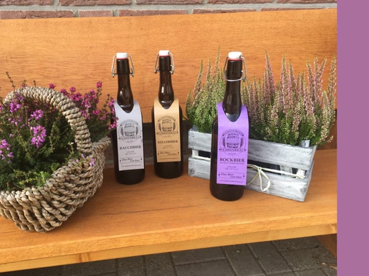 Egestorfer_Fuhrenbraeu.jpg Drei Flaschen Egestorfer Fuhrenbräu vor Erika-Dekorationen auf einer Holzbank.