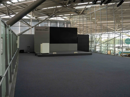 Lounge (4 von 9).jpg Eine leere Bühne im modernen Flughafen mit Glaswänden im Hintergrund.An empty stage in a modern airport with glass walls in the background.