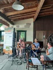 Ingo Halama und Freunde Ingo Halama und Freunde musizieren mit Gitarren unter einem hölzernen Vorbau vor einem Kulturschild.