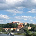 Blick auf die Altstadt von Pirna Stadtansicht mit Fluss im Vordergrund, historischen Gebäuden mit roten Dächern und grünem Turm, umgeben von Bäumen unter blauem Himmel mit Wolken.City view with river in the foreground, historic buildings with red roofs and green tower, surrounded by trees under a blue sky with clouds.Pohled na město s řekou v popředí, historické budovy s červenými střechami a zelenou věží, obklopené stromy pod modrou oblohou s mraky.Widok miasta z rzeką na pierwszym planie, zabytkowe budynki z czerwonymi dachami i zieloną wieżą, otoczone drzewami pod błękitnym niebem z chmurami.Stadsgezicht met rivier op de voorgrond, historische gebouwen met rode daken en groene toren, omringd door bomen onder een blauwe lucht met wolken.Veduta della città con il fiume in primo piano, edifici storici con tetti rossi e torre verde, circondati da alberi sotto un cielo blu con nuvole.