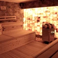 Sauna in der Birkensauna.jpg Eine Holzsauna mit Wänden aus beleuchteten Salzziegeln schafft eine entspannende und warme Atmosphäre.
