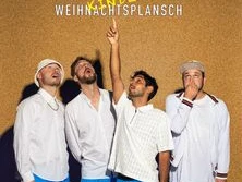 Vier Männer in blauen Shorts posieren vor einer Korkwand, einer zeigt lachend nach oben.