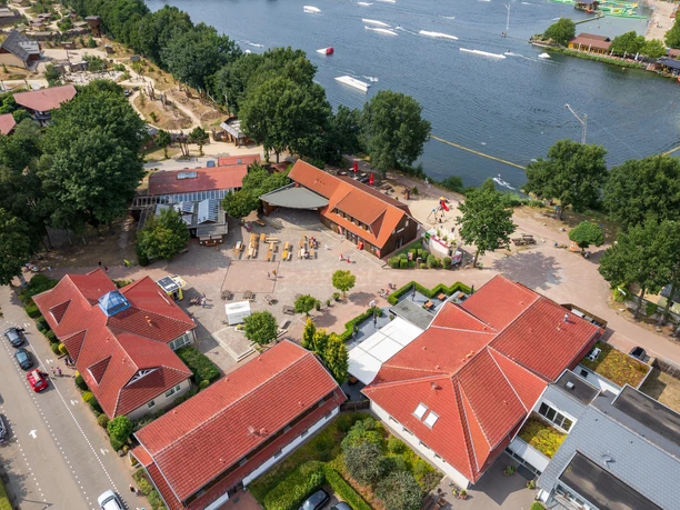 alfsee-drohne(c)tol-foto-jurjen-drenth (8).JPG Freizeitpark neben einem See, mit roten Dächern und grünem Umfeld aus der Vogelperspektive.