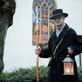 Nachtwächter Roland Zöller (1).jpg Ein Nachtwächter in traditionellem Gewand mit Laterne und Hellebarde vor einer historischen Kirche.