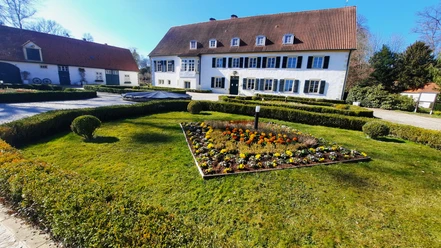 Haus des Gastes FrühjahrTouristik Preußisch Oldendorf.jpg Ein weißes Gebäude mit rotem Ziegeldach und blauen Fensterläden umgeben von gepflegten Gärten.