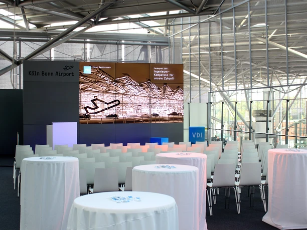 Sitzreihen und Videowall.JPG Moderner Konferenzraum am Köln Bonn Airport mit Stuhlreihen und informativem Bildschirm.</p>