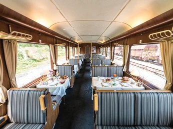 Speisewagen des AKE-RHEINGOLD Innenraum eines nostalgischen Speisewagens mit gedeckten Tischen, gestreiften Sitzen und Lampen.</p>Interior of a nostalgic dining car with set tables, striped seats and lamps.</p> <p