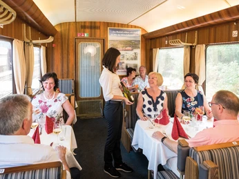 Speisewagen des AKE-RHEINGOLD Im Speisewagen eines Zuges werden lachende Passagiere von einer Kellnerin bedient.</p>Laughing passengers are served by a waitress in the dining car of a train.</p> <p