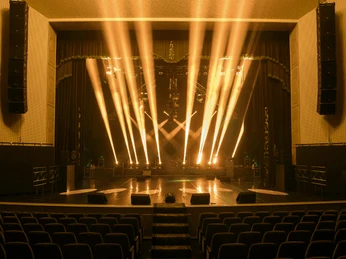 Stage Ein beleuchtetes Theaterbühne-Setup mit intensiven goldenen Lichtstrahlen.An illuminated theater stage setup with intense golden beams of light.
