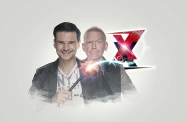 Zaubertrixxer Jung und Thomaszauberer mit Funkenstab, hinter ihm ein großes rotes X, beide lächeln.