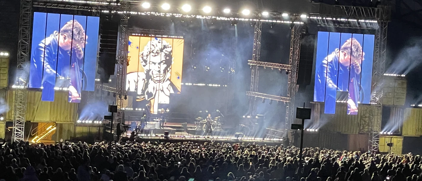 Dagamba Open-Air-Konzert bei Nacht mit beleuchteter Bühne, großer Menschenmenge und Videobildschirm.</p>