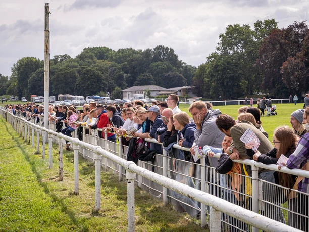 Zuschauer am Renntag People stand tensely at the fence of a racecourse as they watch the race.</p> <p