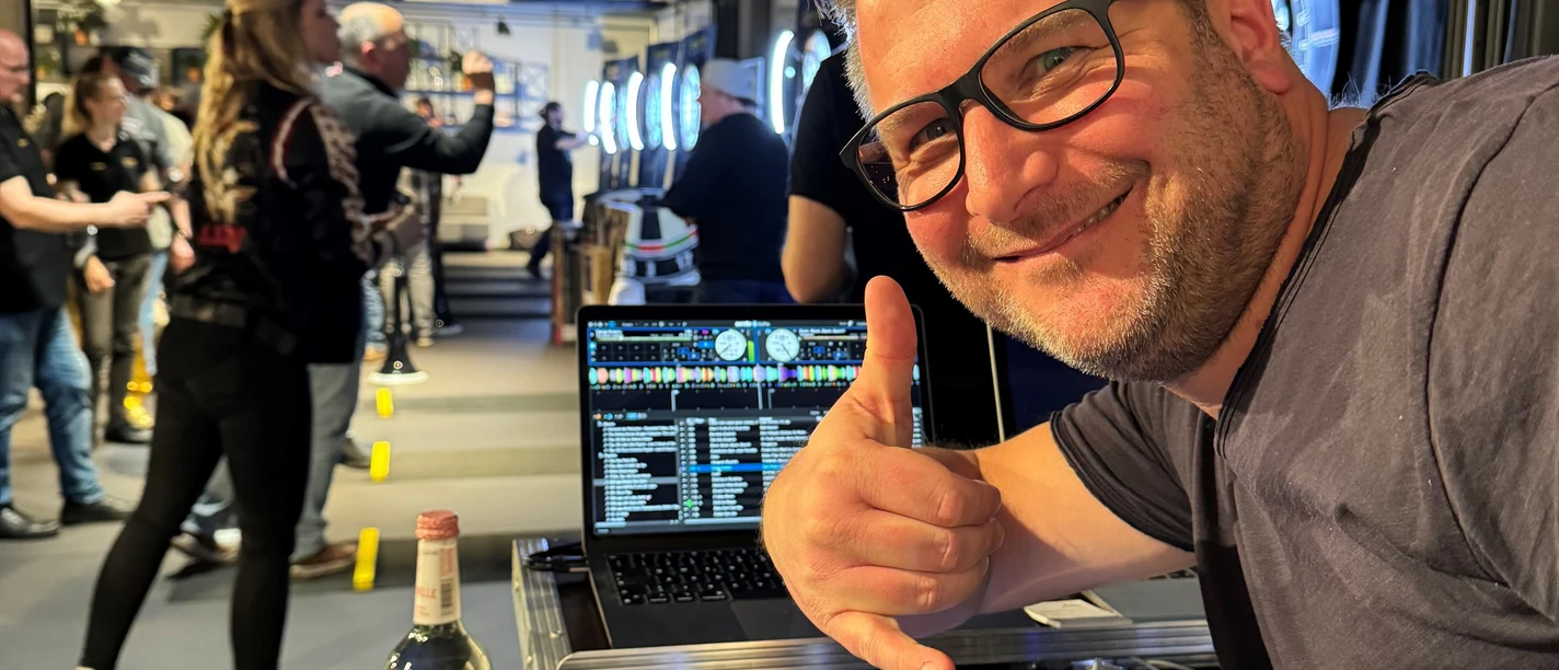 DJ Mr. Easy A DJ with glasses in front of a mixing desk showing an event with people in the background.</p> <p