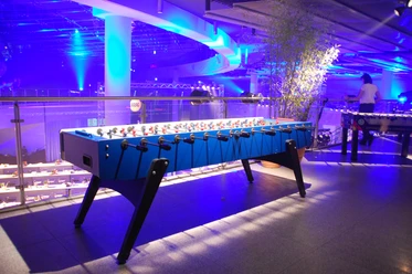 Riesentischkicker 01 An illuminated table football table in a modern, blue design in an atmospheric blue setting.