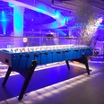 Riesentischkicker 01 Ein beleuchteter Tischfußballtisch in modernem, blauem Design in einer stimmungsvoll blauen Umgebung.An illuminated table football table in a modern, blue design in an atmospheric blue setting.