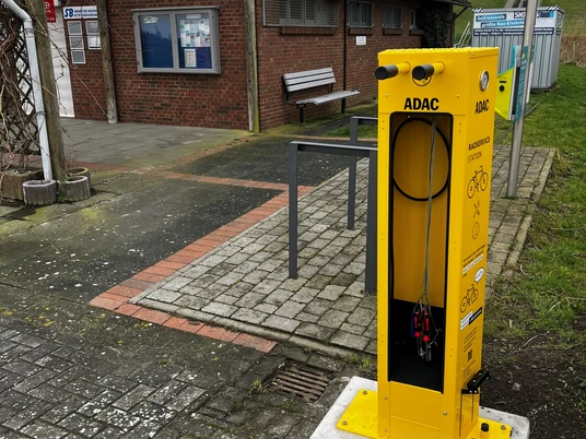 Fahrradflickstation vom ADAC am Trockenstrand Upleward Gelbe ADAC-Fahrradflickstation mit Werkzeugen und Luftpumpe vor Backsteingebäude am Trockenstrand.