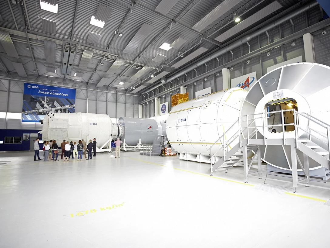 Europäisches Astronautenzentrum Mockup von Raumfahrtmodulen in einem modernen, großen Hochtechnologielabor mit Besuchern und ESA-Logo.Mockup of space modules in a modern, large high-tech laboratory with visitors and ESA logo.