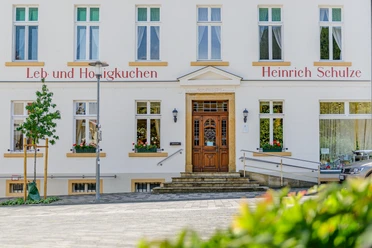 Ladencafé Schulze Das Bild zeigt die Fassade einer traditionellen Lebkuchen-Bäckerei mit Stufen und Blumendekoration.
