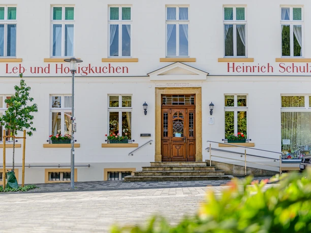 Ladencafé Schulze Das Bild zeigt die Fassade einer traditionellen Lebkuchen-Bäckerei mit Stufen und Blumendekoration.