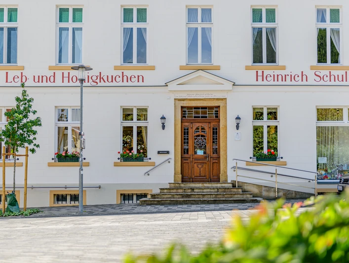 Ladencafé Schulze Das Bild zeigt die Fassade einer traditionellen Lebkuchen-Bäckerei mit Stufen und Blumendekoration.