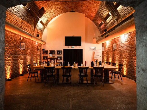 brauwelt-koeln-brauhaus-tagung.jpg Gemütlicher, beleuchteter Backsteingewölbekeller mit langer Tafel und Stühlen, ideal für Events.