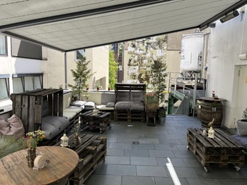 Terrasse ANNO 1858.jpg <p>Sonnige Terrasse mit gemütlichen Sitzgelegenheiten aus Paletten und grünen Pflanzen in der Umgebung.</p><p>Sunny terrace with cozy seating made of pallets and green plants in the area.</p>