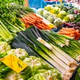 Wochenmarkt (2).png Frisches Gemüse in leuchtenden Farben, darunter Karotten, Lauch und Kohl, auf einem Wochenmarktstand.